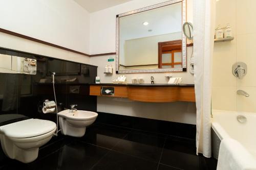 a bathroom with a sink and a toilet and a mirror at Holiday Inn Kuwait by IHG in Kuwait
