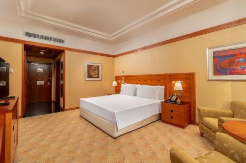 a bedroom with a large white bed and a couch at Holiday Inn Kuwait by IHG in Kuwait