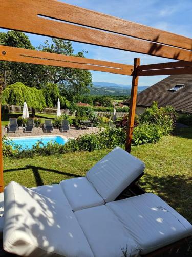 une pergola avec un banc à côté d'une piscine dans l'établissement Villanath, à Bellegarde-sur-Valserine