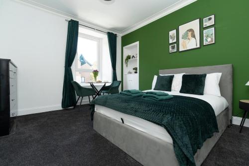 a green bedroom with a bed and a table at Studio flat in Dundee in Dundee