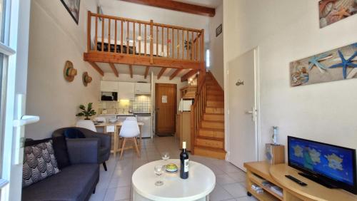 un salon avec un canapé et une télévision et une cuisine dans l'établissement Meschers sur Gironde - MAISONNETTE de VACANCES - terrasse - proche PLAGE, à Meschers-sur-Gironde