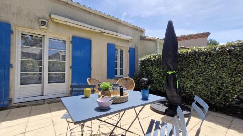 une table bleue et des chaises devant une maison dans l'établissement Meschers sur Gironde - MAISONNETTE de VACANCES - terrasse - proche PLAGE, à Meschers-sur-Gironde