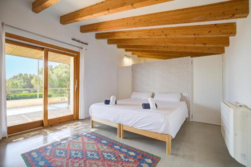 a bedroom with a white bed and a large window at Can Cadernera by Rentallorca in Can Picafort
