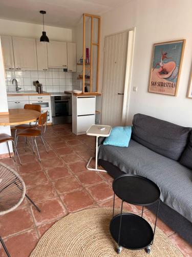 un salon avec un canapé et une table et une cuisine dans l'établissement Charmante maison de pêcheur, à Aigues-Mortes