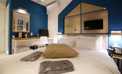 a bedroom with a large white bed with a blue wall at NU Hotel in Cheonan