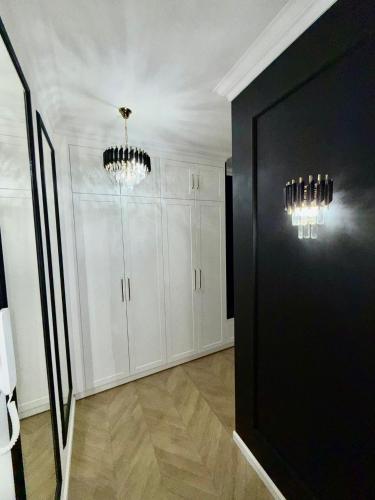 a room with white cabinets and chandeliers at Just Unique black in Poznań