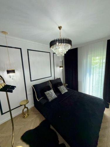a bedroom with a large black bed and a chandelier at Just Unique black in Poznań