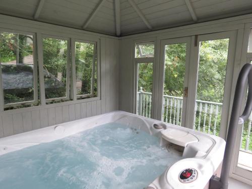 eine Badewanne in einem Zimmer mit Fenstern in der Unterkunft Blaenfforest Rose Cottage Newcastle Emlyn in Capel-Ifan