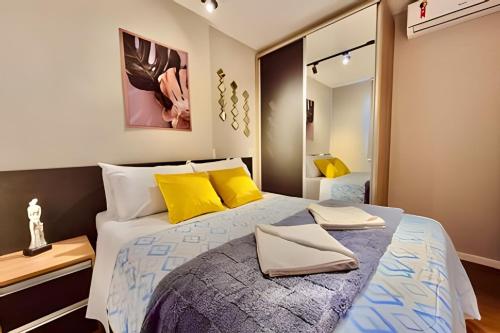 a bedroom with a large bed with yellow pillows at VERSáTIL - Apto de 1 quarto in Curitiba