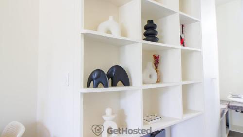une étagère blanche avec des vases et des chaussures dessus dans l'établissement Paris Expo - Charming Apartment - GetHosted, à Paris