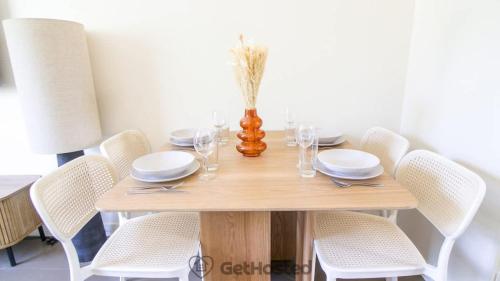 - une table en bois avec des chaises blanches et un vase dans l'établissement Paris Expo - Charming Apartment - GetHosted, à Paris