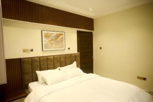 a bedroom with a bed with white sheets and pillows at Abram Hills Hotel Ltd in Koforidua
