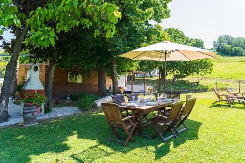 a wooden table with an umbrella in a yard at Villetta Collina degli Angeli con ampio giardino in Montelabbate