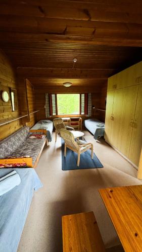 a room with three beds and a table and benches at Kyyronkaita in Mikkeli