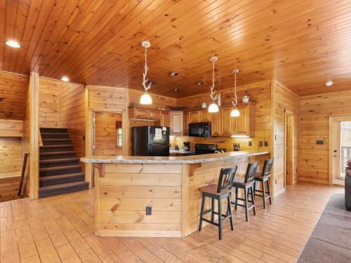 a kitchen with wooden walls and a bar with chairs at The Great Escape II, 5 Bedrooms, Sleeps 17, Game Room, Pool Access, Theater in Gatlinburg