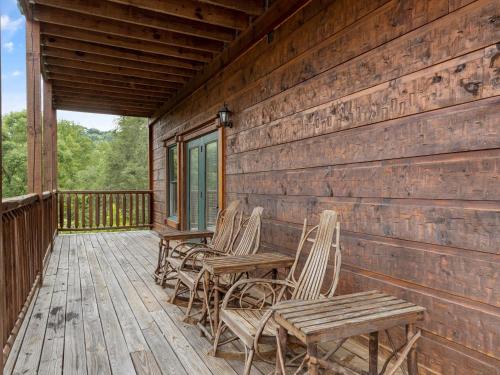 a porch with chairs and tables on a cabin at The Great Escape II, 5 Bedrooms, Sleeps 17, Game Room, Pool Access, Theater in Gatlinburg