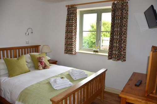 a teddy bear sitting on a bed in a bedroom at Hazel - 3 Bed accessible holiday cottages in Tregoney