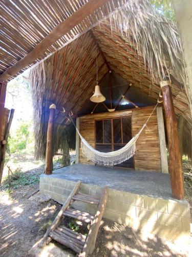a hammock hanging from a thatched hut with a chair at Pal Mar our beach house 