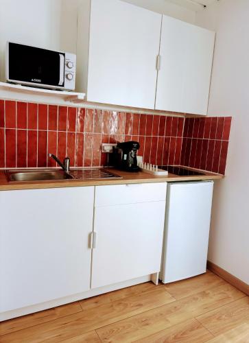 une cuisine avec des armoires blanches et un micro-ondes dans l'établissement Le Nid des Salins - Studio Mer & Terrasse, à Hyères