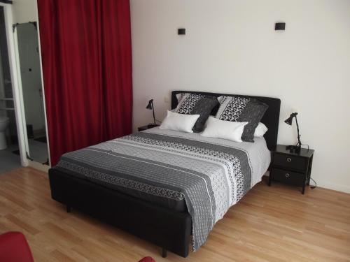 une chambre avec un grand lit avec un rideau rouge dans l'établissement A coté des plages et des marais salants de Guérande, à Guérande