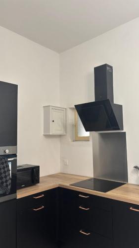 une cuisine avec des armoires noires et un four à plaques de cuisson dans l'établissement L'Appart Saint-Sever, à Agde