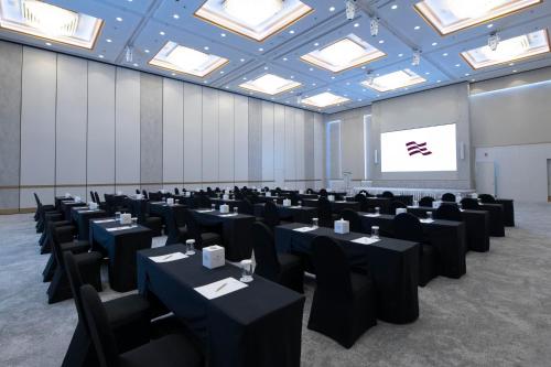 a room with black tables and chairs and a screen at Crowne Plaza Bahrain by IHG in Manama