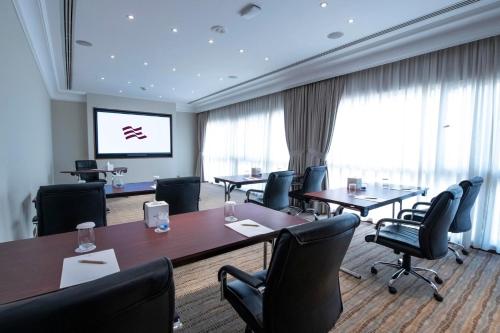 a conference room with tables and chairs and a projection screen at Crowne Plaza Bahrain by IHG in Manama
