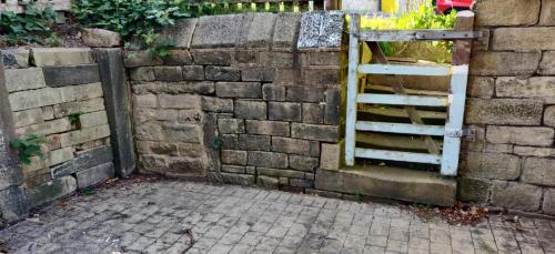 a brick wall with a gate and a brick sidewalk at Grange Dene Cottage in Mytholmroyd