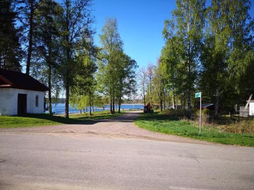 a road next to a lake with a building and trees at Naturparadies und Angeloase Borgvik in Borgvik