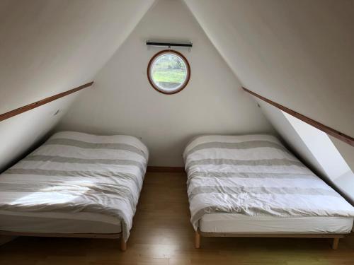 deux lits dans une chambre mansardée avec une fenêtre dans l'établissement Jolie petite maison bord de mer, à Pénestin
