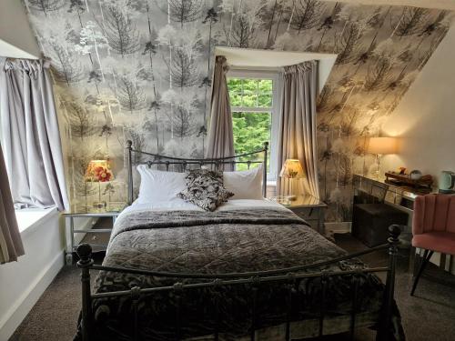 a bedroom with a bed and a wall covered in wallpaper at Eagle View Guest House in Newtonmore