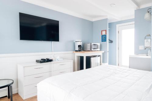 a bedroom with a white bed and a flat screen tv at The Montauk Soundview in Montauk