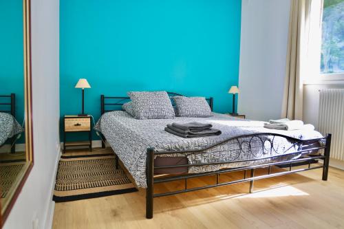 une chambre avec un lit avec un mur bleu dans l'établissement La Forêt - Jardin, Forêt de Fontainebleau, à Bois-le-Roi