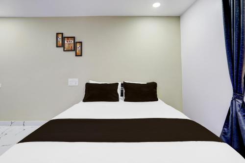a bedroom with a white bed with black pillows at Hotel O PRAMOD GUEST INN in Nellore