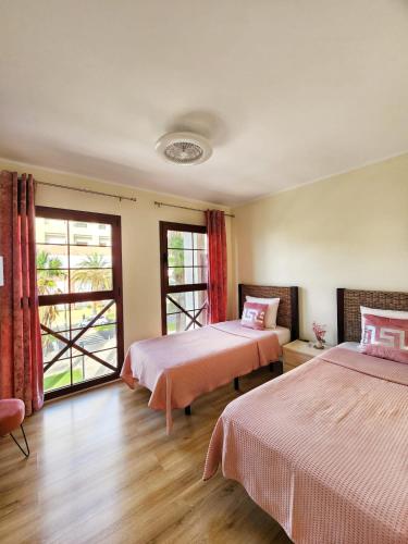 a hotel room with two beds and a window at Luxury unique central flat with 2 swimming pools in Playa de las Americas