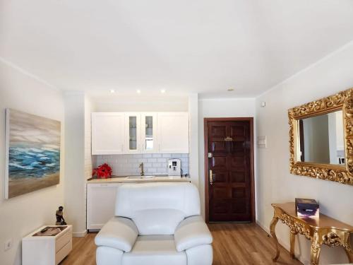 a living room with a white chair and a mirror at Luxury unique central flat with 2 swimming pools in Playa de las Americas
