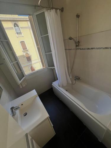 une salle de bain avec une baignoire, un lavabo et une fenêtre dans l'établissement Charmant appartement avec terrasse en plein cœur de Nice à deux pas de la mer !, à Nice