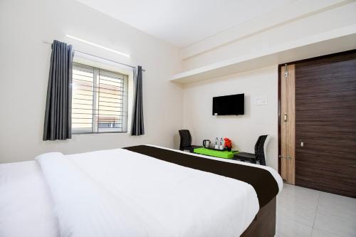 Un dormitorio con una cama blanca y un televisor. en Hotel O AMRITA PREMIUM, en Bhubaneshwar