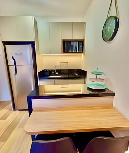 a kitchen with a refrigerator and a counter with chairs at Novinho, Lindo e Moderno C/ Ar Cond. in Curitiba