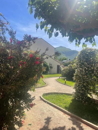 a winding road with flowers and a house in the background at Studio avec piscine in Sisco