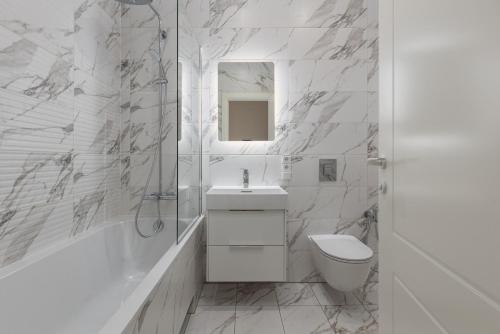 a white bathroom with a sink and a toilet at Gatve apartment in Rīga