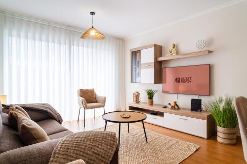 a living room with a couch and a tv at GuestReady - Duplex paradise in Caniço in Caniço