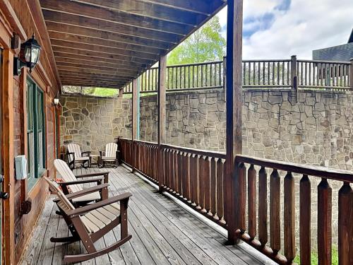 a deck with two chairs and a stone wall at The Great Escape II, 5 Bedrooms, Sleeps 17, Game Room, Pool Access, Theater in Gatlinburg