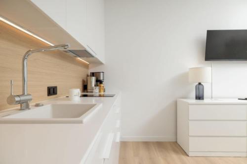 cocina blanca con fregadero y TV en PINEA Apartamenty, en Pobierowo