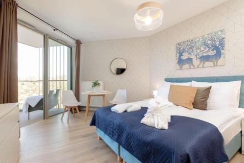 a bedroom with a blue and white bed and a table at PINEA Apartamenty in Pobierowo