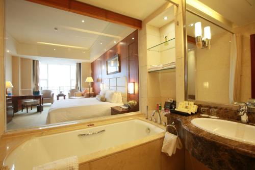 un bagno con vasca e una camera da letto con un letto di Beijing Jingyi Hotel a Pechino