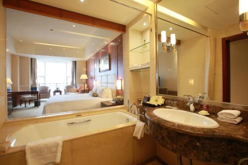 a bathroom with a tub and a bedroom with a bed at Beijing Jingyi Hotel in Beijing