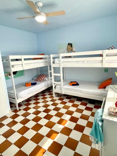 a room with white bunk beds and a checkered floor at MASIA EN COSTA DORADA y CLIMATIZADA in Reus