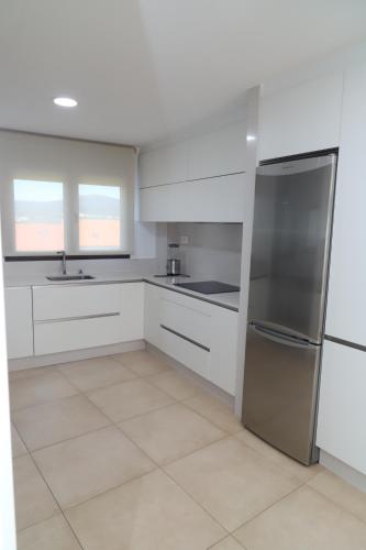 a kitchen with white cabinets and a stainless steel refrigerator at Soledá e Pepa II in Noya