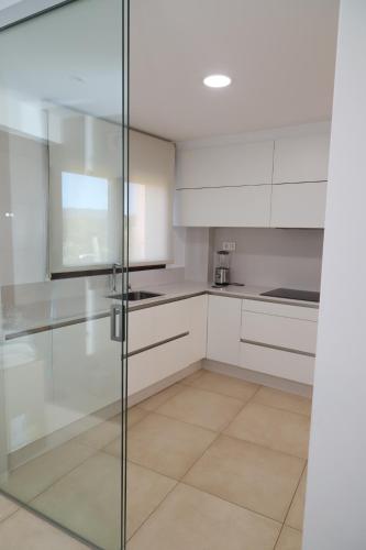 a kitchen with white cabinets and a glass door at Soledá e Pepa II in Noya
